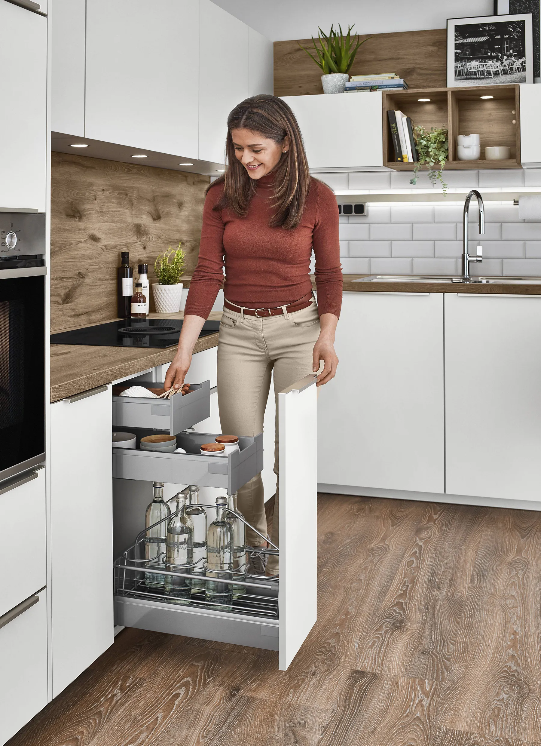 Woman using a pull-out storage unit in a bright kitchen with white cabinets and wood accents, showcasing the influence of colour psychology in creating a warm, organised space. Woman using a pull-out storage unit in a bright kitchen with white cabinets and wood accents, showcasing the influence of colour psychology in creating a warm, organised space.