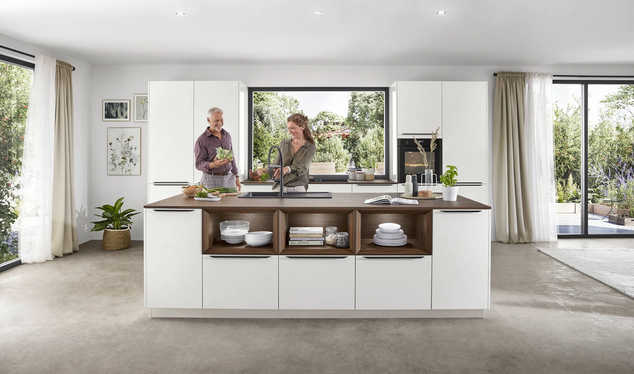 Couple preparing food in a bright kitchen with white cabinets, large windows, and a central island, showcasing a design that embraces natural light. Couple preparing food in a bright kitchen with white cabinets, large windows, and a central island, showcasing a design that embraces natural light.