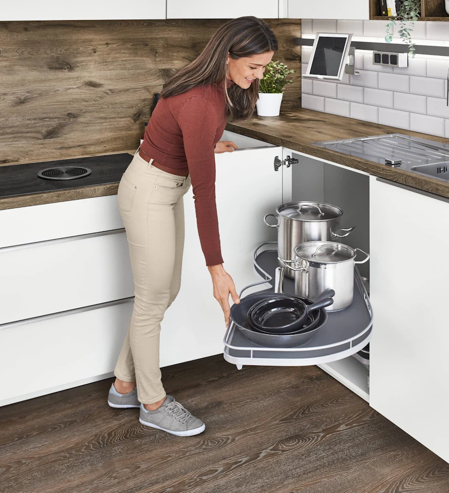 Person using a corner cabinet pull-out unit Person using a corner cabinet pull-out unit